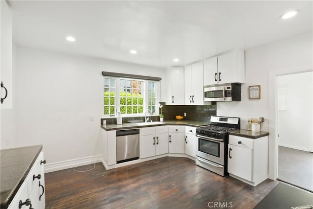 kitchen featuring white cabinets, dark countertops, appliances with stainless steel finishes, and dark wood finished floors