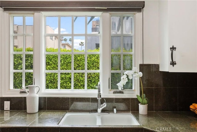 room details featuring white cabinets, tasteful backsplash, tile countertops, and a sink