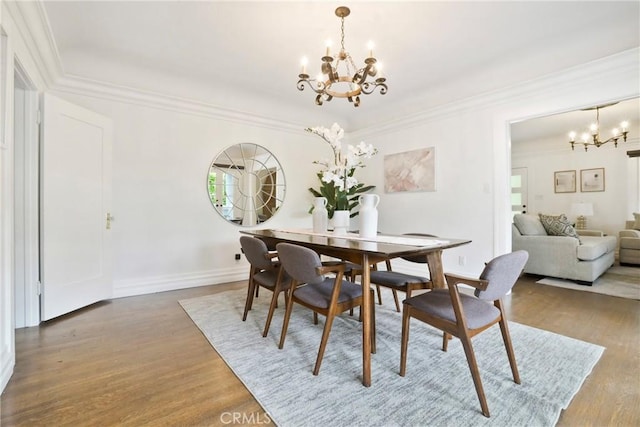 dining area with baseboards, wood finished floors, an inviting chandelier, and crown molding