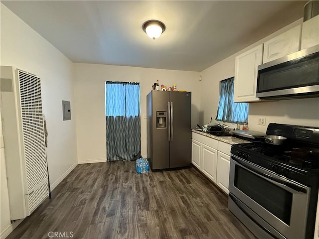 kitchen with a heating unit, white cabinetry, stainless steel appliances, electric panel, and dark wood-type flooring