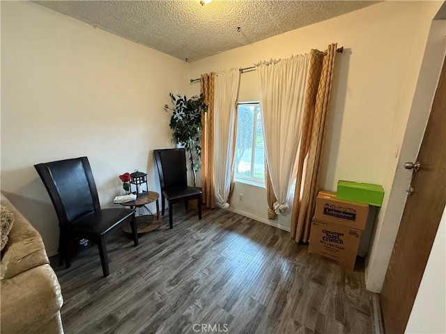 living area with baseboards, wood finished floors, and a textured ceiling