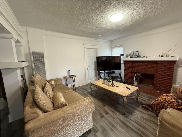 living room with a heating unit, a textured ceiling, wood finished floors, and a brick fireplace