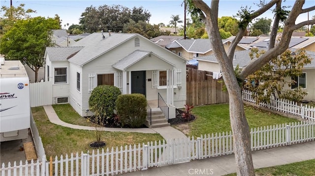 bungalow-style house featuring a fenced front yard, roof with shingles, and a front yard