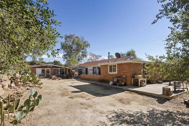 rear view of property featuring brick siding and a patio