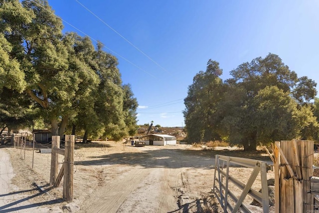 view of yard featuring dirt driveway, a carport, and fence