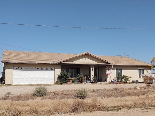 ranch-style home with stucco siding, driveway, covered porch, and a garage