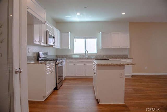 1334 Pinehurst Dr, Calimesa, CA 92320 - kitchen featuring appliances with stainless steel finishes, a kitchen island, white cabinets, a sink, and light wood-type flooring