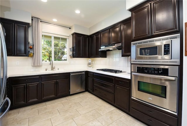 kitchen featuring decorative backsplash, appliances with stainless steel finishes, a sink, light countertops, and under cabinet range hood