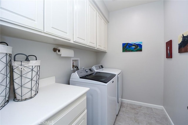 washroom with baseboards, cabinet space, and washer and dryer