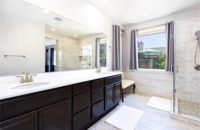 full bath featuring double vanity, a sink, tile patterned flooring, and a shower stall