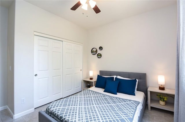 tiled bedroom with baseboards, ceiling fan, and a closet
