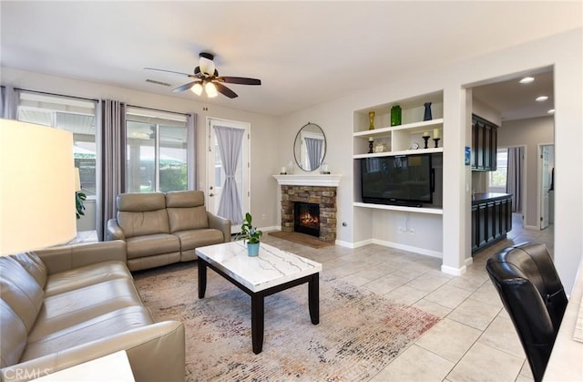 living area featuring visible vents, a fireplace, ceiling fan, built in shelves, and light tile patterned floors