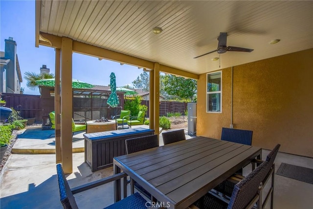 view of patio featuring a fenced backyard, ceiling fan, a fire pit, and outdoor dining space