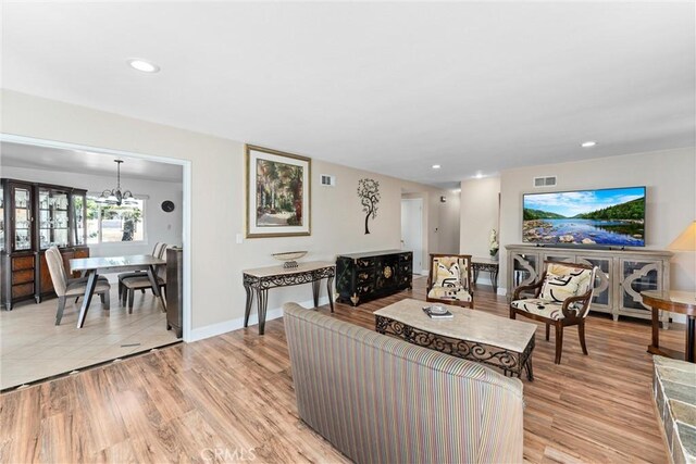 living area featuring a chandelier, light wood-style flooring, baseboards, visible vents, and recessed lighting