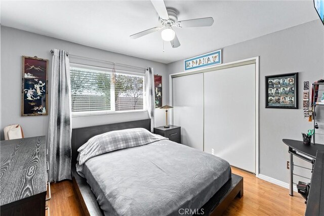bedroom featuring wood finished floors, a closet, a ceiling fan, and baseboards