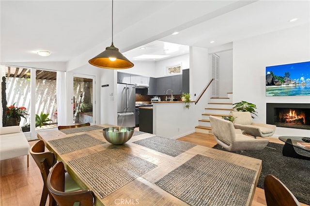 2402 Aspen Dr, Los Angeles, CA 90068 - dining room featuring recessed lighting, a warm lit fireplace, stairway, and light wood-type flooring
