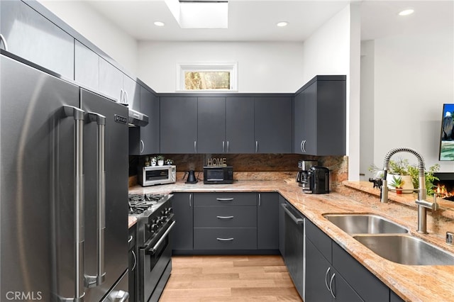 2402 Aspen Dr, Los Angeles, CA 90068 - kitchen with premium appliances, a sink, light wood-style floors, exhaust hood, and light stone countertops