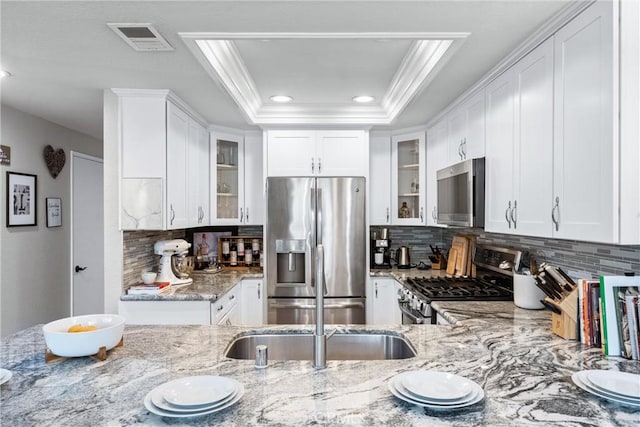 kitchen featuring light stone counters, visible vents, ornamental molding, and stainless steel appliances