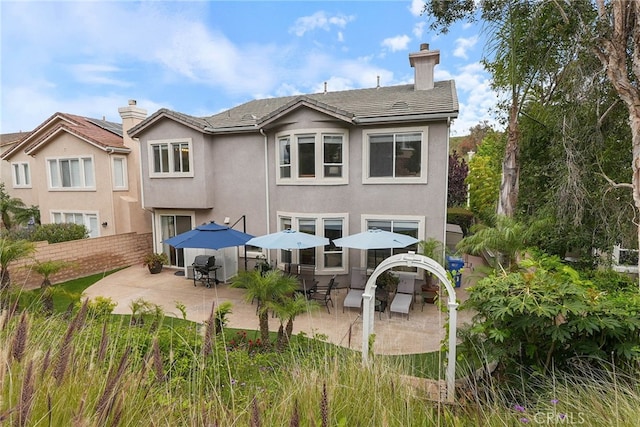 back of property with fence, a chimney, a patio area, and stucco siding