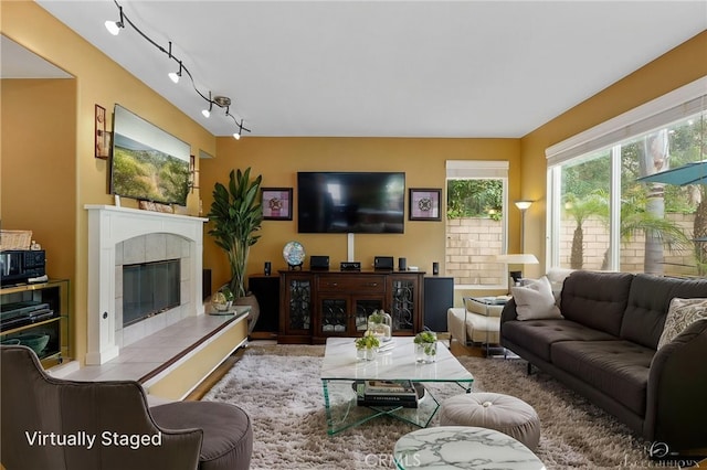 living room featuring rail lighting, a tile fireplace, and wood finished floors
