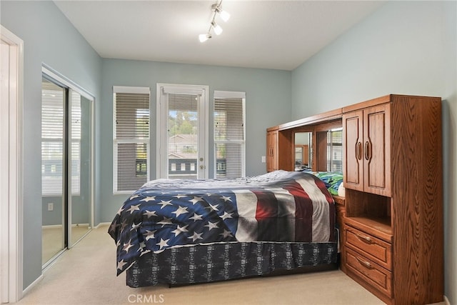 bedroom featuring baseboards, light colored carpet, access to exterior, and rail lighting