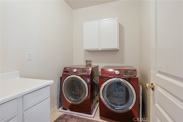 clothes washing area featuring light tile patterned floors, baseboards, washing machine and dryer, and cabinet space