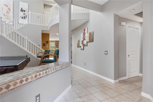 foyer entrance with baseboards, light tile patterned floors, visible vents, and stairway