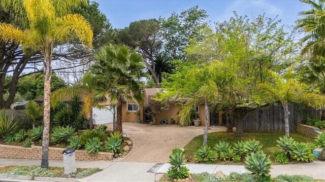 exterior space featuring an attached garage, decorative driveway, and fence