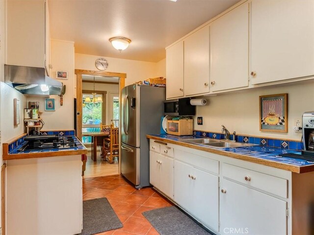 kitchen with white cabinets, appliances with stainless steel finishes, under cabinet range hood, and light tile patterned floors