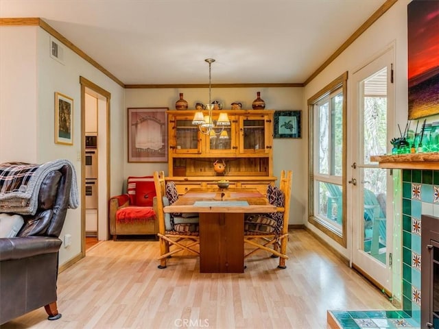 dining area featuring light wood-style floors, crown molding, and a notable chandelier