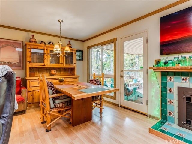 dining space with an inviting chandelier, ornamental molding, and light wood-style floors