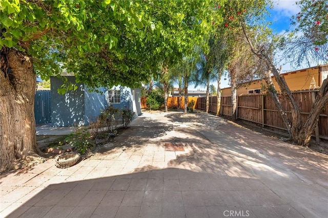 view of yard featuring a patio area, driveway, and a fenced backyard