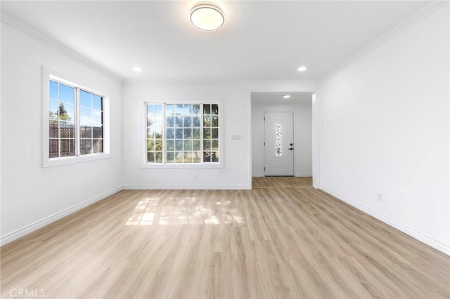 unfurnished living room with light wood-type flooring, a healthy amount of sunlight, and crown molding