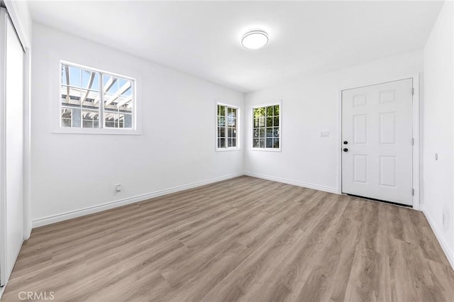 unfurnished room featuring baseboards and light wood-type flooring