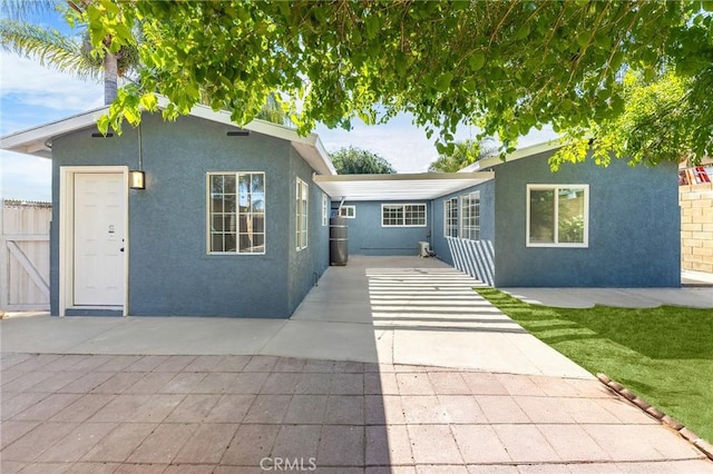 view of front of home featuring stucco siding, fence, and a patio area