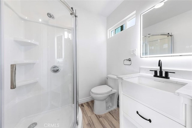 bathroom with wood finished floors, vanity, toilet, and a stall shower