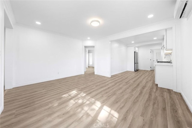 unfurnished living room featuring recessed lighting, an AC wall unit, a sink, light wood-style floors, and crown molding