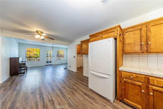 51192 Bon Veu Dr, Oakhurst, CA 93644 - kitchen with freestanding refrigerator, ceiling fan, dark wood-type flooring, and brown cabinets