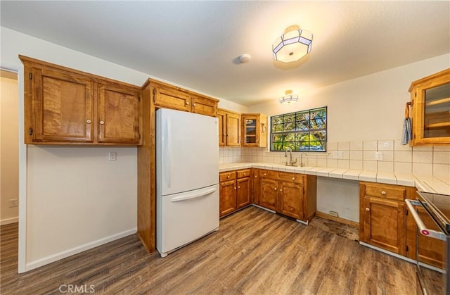 51192 Bon Veu Dr, Oakhurst, CA 93644 - kitchen with freestanding refrigerator, brown cabinets, dark wood finished floors, stove, and backsplash