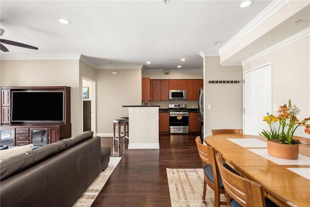living room with ceiling fan, recessed lighting, dark wood-type flooring, crown molding, and baseboards