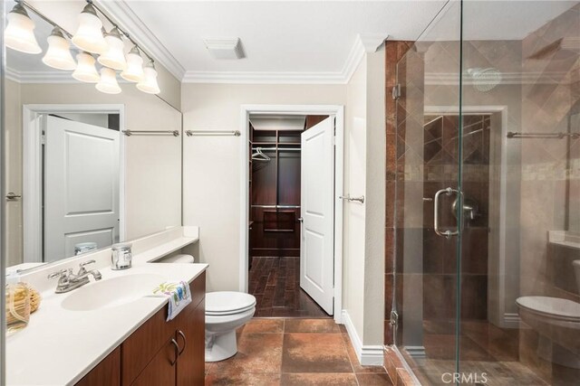 full bathroom featuring toilet, ornamental molding, a shower stall, vanity, and a walk in closet