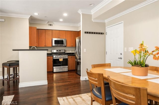 kitchen with stainless steel appliances, brown cabinets, dark countertops, ornamental molding, and dark wood finished floors
