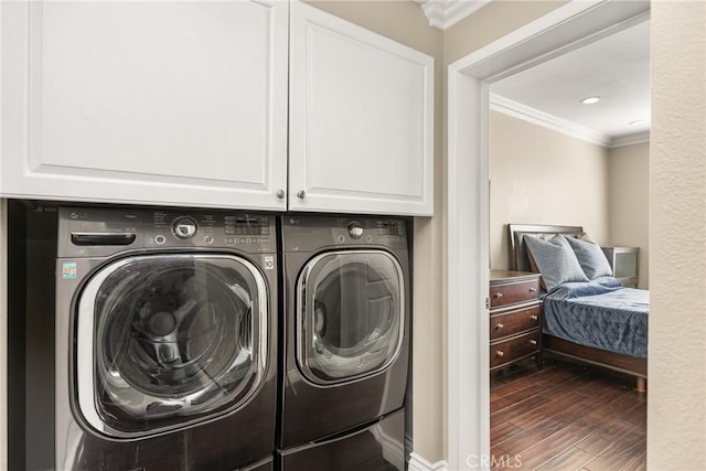 clothes washing area featuring ornamental molding, washer and clothes dryer, cabinet space, and dark wood-style floors