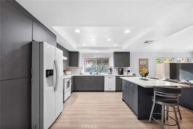 7701 Quimby Ave, West Hills, CA 91304 - kitchen featuring white appliances, a raised ceiling, light countertops, open floor plan, and a kitchen island