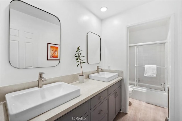 7701 Quimby Ave, West Hills, CA 91304 - bathroom featuring double vanity, enclosed tub / shower combo, and wood finished floors