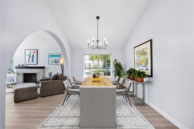 7701 Quimby Ave, West Hills, CA 91304 - dining room with a chandelier, a high end fireplace, light wood-style flooring, high vaulted ceiling, and arched walkways