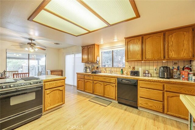 kitchen with gas range, backsplash, tile counters, and black dishwasher