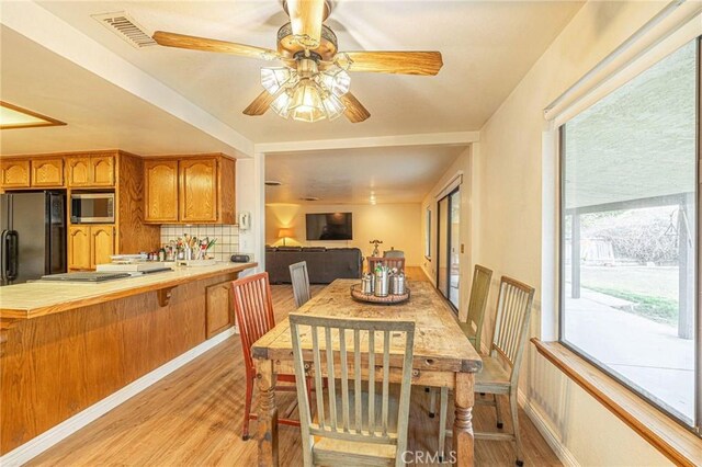 dining room featuring a ceiling fan, light wood-style floors, visible vents, and plenty of natural light