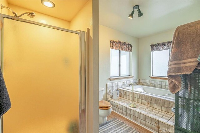 full bathroom with a shower stall, a garden tub, toilet, and wood finished floors