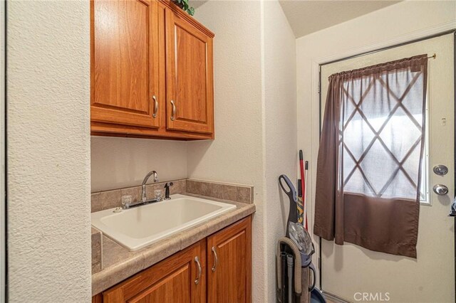 clothes washing area featuring a textured wall and a sink